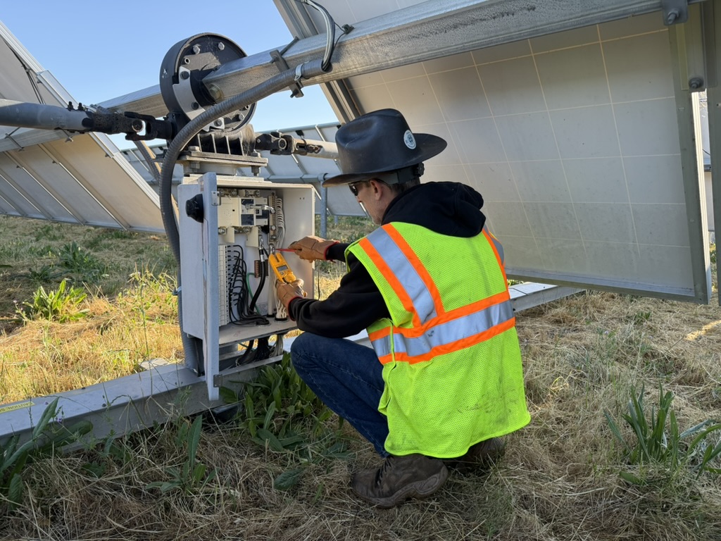 ETS technician performing electrical diagnostics at solar array junction box